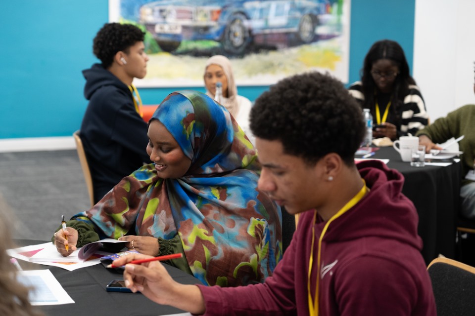 Young people writing at a table as part of a workshop
