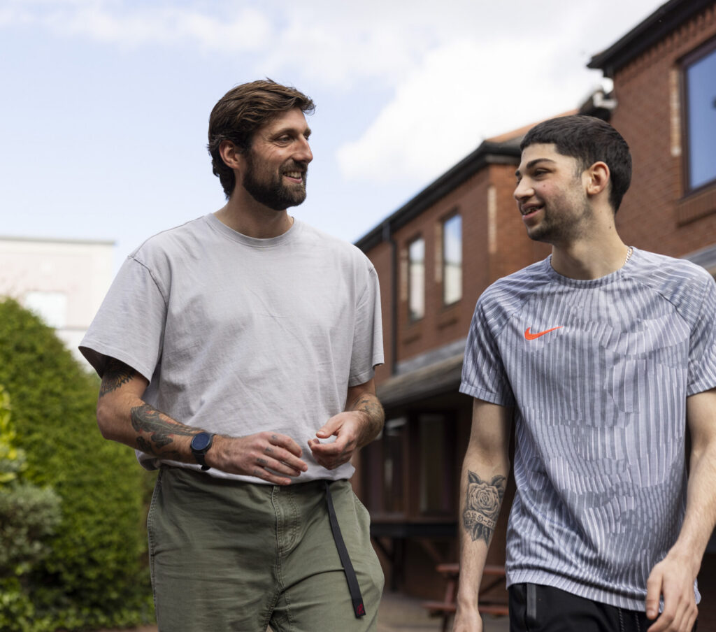 Care experienced young person chatting animatedly to adult coach as they walk outside